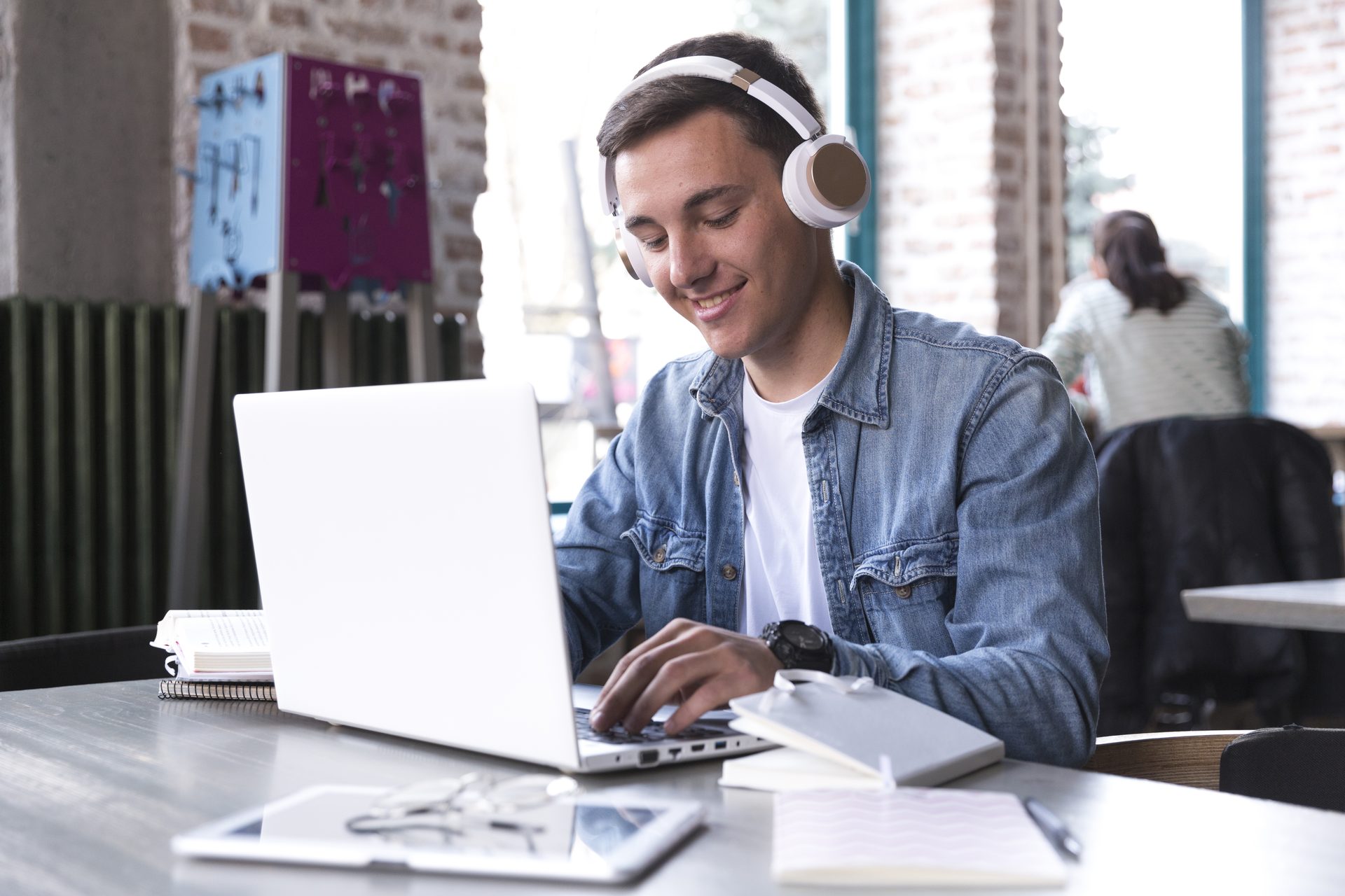 Joven con auriculares escribiendo en su laptop en un espacio de trabajo